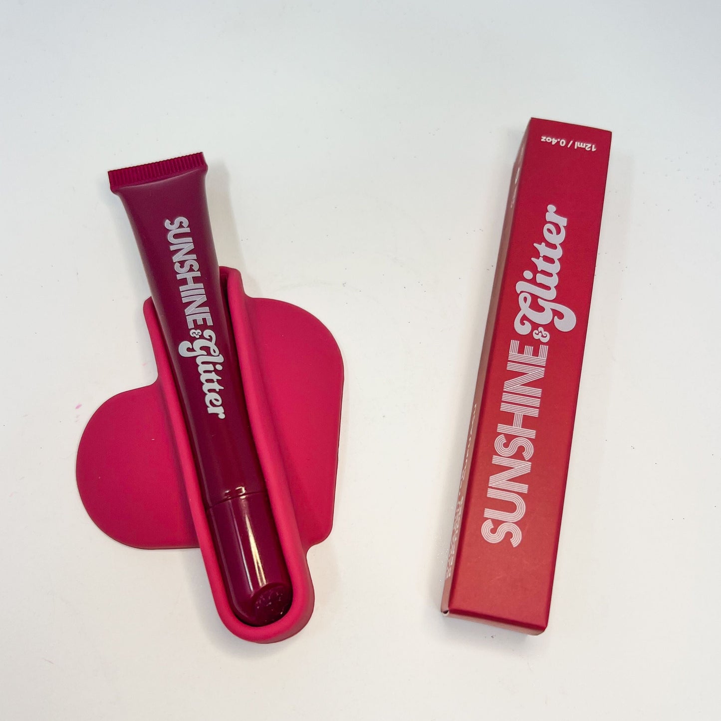 Pink lip gloss with packaging on a white background
