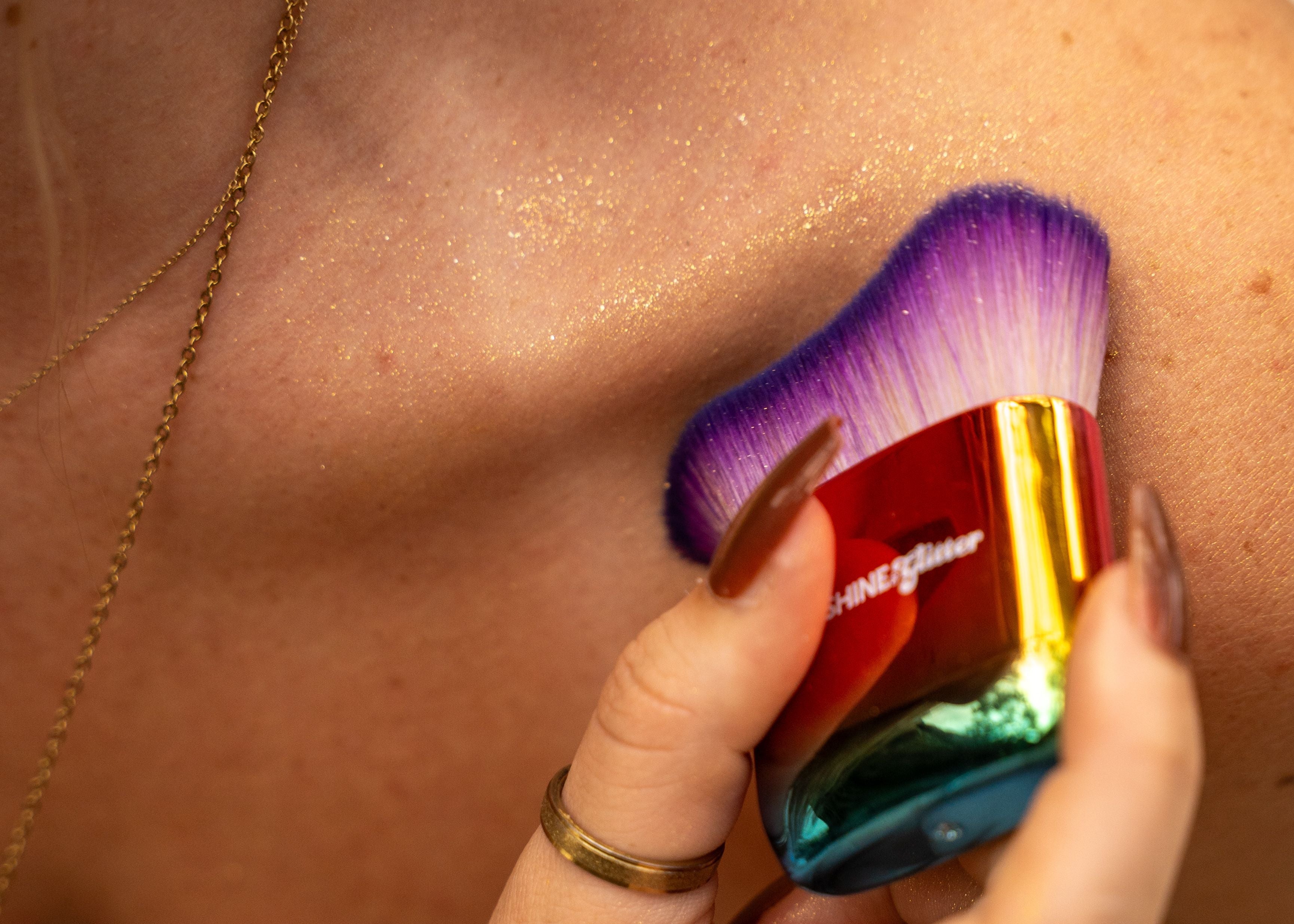 Hand holding a colorful makeup brush against a blurred background